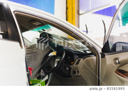 Male specialist applying window tinting film on the car. 83581993
