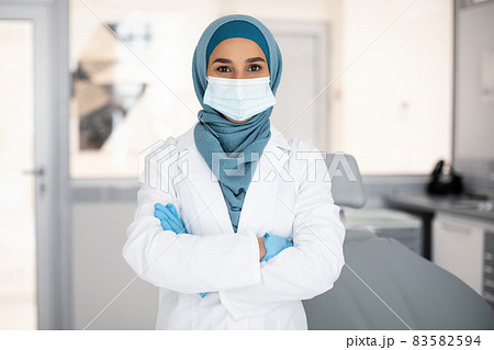 Confident Muslim Female Stomatologist Wearing Hijab And Uniform Posing In Clinic Interior Confident Muslim Female Stomatologist Wearing Hijab And Uniform Posing In Clinic Interior 83582594