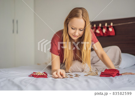 Woman making Christmas advent calendar. Pouches on a rope 83582599