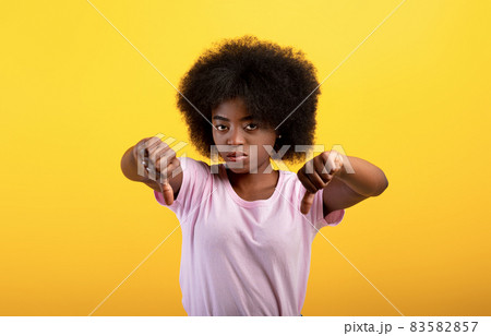 Dislike. Unhappy black lady showing thumb down gesture, displeased young woman expressing disapproval Dislike. Unhappy black lady showing thumb down gesture, displeased young woman expressing disapproval 83582857