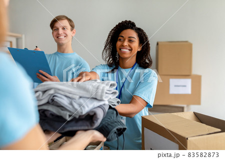 Happy diverse volunteers sorting, packing clothes in cardboard boxes, working together on donation project Happy diverse volunteers sorting, packing clothes in cardboard boxes, working together on donation project 83582873