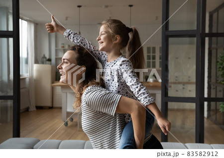 Joyful young mother carrying on back laughing small kid daughter. Joyful young mother carrying on back laughing small kid daughter. 83582912