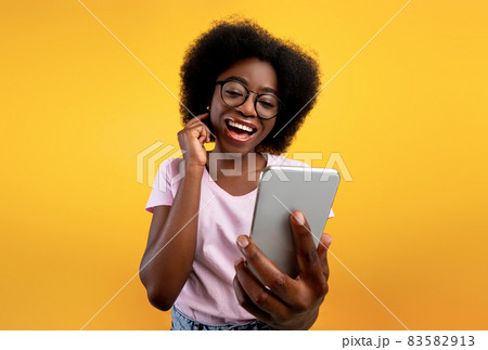 Happy african american lady using smartphone and making video call, smiling at cellphone camera over yellow background Happy african american lady using smartphone and making video call, smiling at cellphone camera over yellow background 83582913