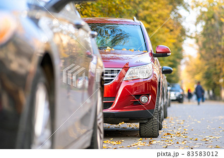 Cars parked in a row on a city street side on bright autumn day. 83583012