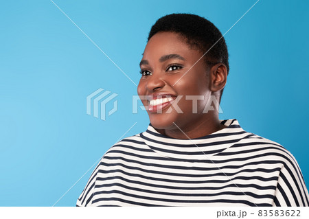 Portrait Of Cheerful Overweight African Lady Looking Aside, Blue Background Portrait Of Cheerful Overweight African Lady Looking Aside, Blue Background 83583622