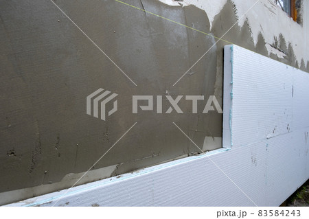 Installation of styrofoam insulation sheets on house facade wall for thermal protection. 83584243