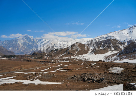 In a mountain valley, a breathtaking landscape of giant covered mountains in the background In a mountain valley, a breathtaking landscape of giant covered mountains in the background 83585208
