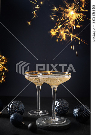 Festive champagne in wine glasses and Christmas blue baubles on dark background. 2022 New Year party Festive champagne in wine glasses and Christmas blue baubles on dark background. 2022 New Year party 83586368