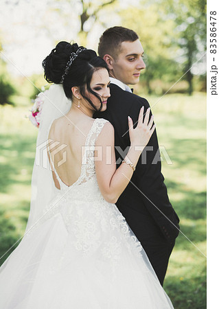 Newly married couple running and jumping in park while holding hands Newly married couple running and jumping in park while holding hands 83586478