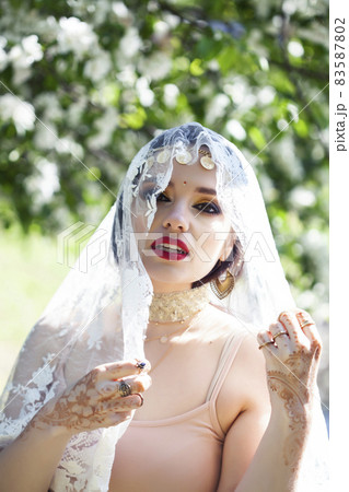 young pretty indian girl in jewelry and veil posing cheerful happy smiling in green park, lifestyle people concept 83587802