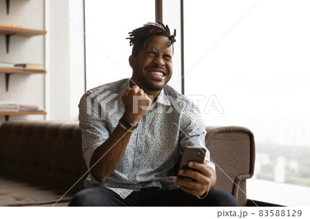 Overjoyed young mixed race man celebrating internet success. Overjoyed young mixed race man celebrating internet success. 83588129