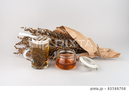 Glass of herb tea, tea strainer, honey and Wormwood twigs wrapped in brown paper. Glass of herb tea, tea strainer, honey and Wormwood twigs wrapped in brown paper. 83588708