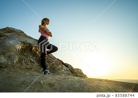 Woman hiker leaning on a big rock enjoying warm summer day. Young female climber resting during sports activity in nature. Active recreation in nature concept. 83588744