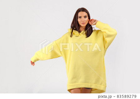Young pretty woman wearing yellow hoodie and gray cycling shorts on white background Young pretty woman wearing yellow hoodie and gray cycling shorts on white background 83589279