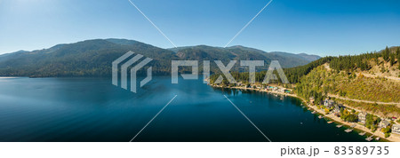 Aerial panoramic view of a residential homes by a lake and mountains. Aerial panoramic view of a residential homes by a lake and mountains. 83589735