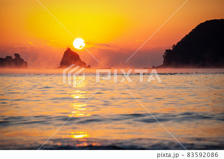 太平洋日向灘に昇る日出で黄昏色に染まった日南海岸の贄波浜と鳥帽子島に松島と黒島と間に広がる毛嵐 83592086