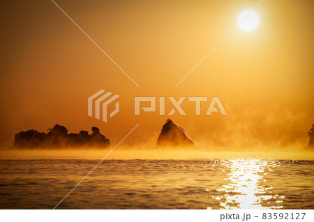 太平洋日向灘に昇る日出で黄昏色に染まった日南海岸の贄波浜と鳥帽子島に松島と黒島と間に広がる毛嵐 83592127