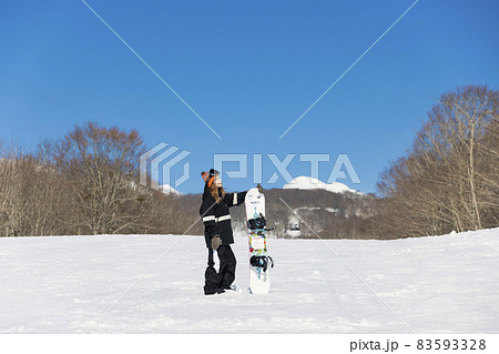 スノボを持ってカメラ目線で立つ若い女性　スノーボードイメージ　 83593328