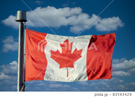A Waving Canadian flag with a blue sky with clouds 83593429