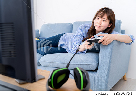 ソファに寝そべり寛ぎながらネットゲーム（オンラインゲーム）をプレイする女性 83596751
