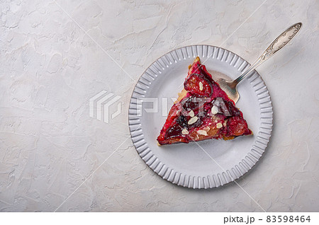 Piece of plum pie on a light plate with a shoulder blade 83598464