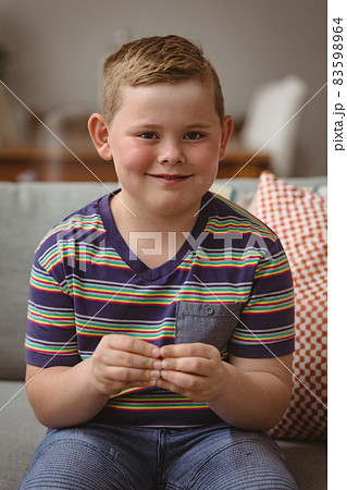 Portrait of caucasian boy making hand gestures sitting on the couch at home 83598964