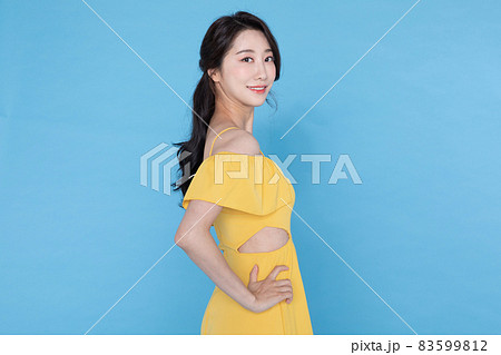 side view of smiling beautiful Korean Asian woman in summer yellow dress, skyblue background side view of smiling beautiful Korean Asian woman in summer yellow dress, skyblue background 83599812