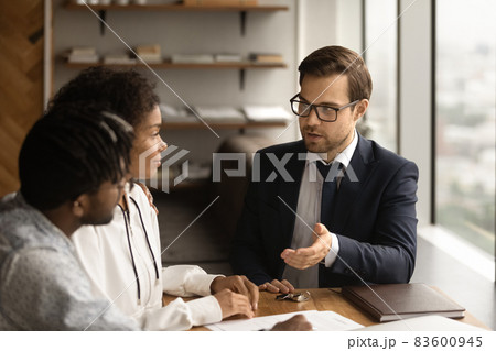 Focused skilled young male realtor consulting clients at office meeting. 83600945