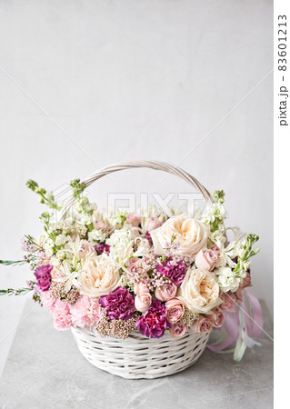 Flower arrangement in Wicker basket. Beautiful bouquet of mixed flowers in woman hand. Handsome fresh bouquet. Small flower shop and Flowers delivery. 83601213