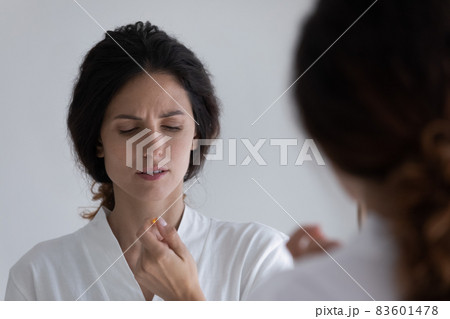 Young unhealthy frowning woman in bathrobe holds pill in hand Young unhealthy frowning woman in bathrobe holds pill in hand 83601478
