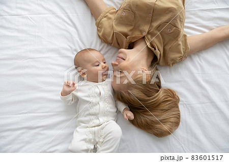 Top view loving young mother and baby lying on bed Top view loving young mother and baby lying on bed 83601517