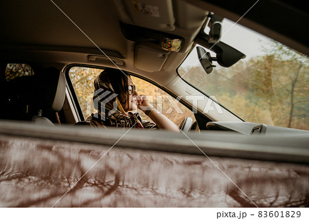 A young beautiful girl in a headscarf is sitting in an expensive brown car. 83601829