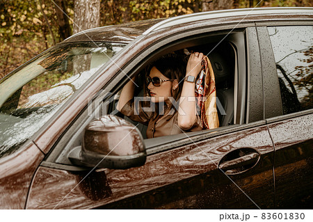 A young beautiful girl in a headscarf is sitting in an expensive brown car. A young beautiful girl in a headscarf is sitting in an expensive brown car. 83601830