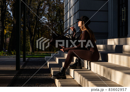 Fashionable young brunette woman with long legs wearing Solid Long Sleeve Bodycon One Piece Jumpsuits posing with a leather brown travel bag 83602957