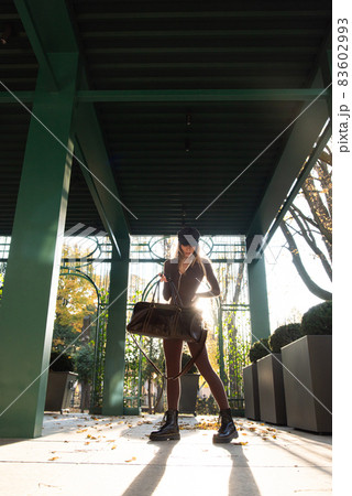 Fashionable young brunette woman with long legs wearing Solid Long Sleeve Bodycon One Piece Jumpsuits posing with a leather brown travel bag Fashionable young brunette woman with long legs wearing Solid Long Sleeve Bodycon One Piece Jumpsuits posing with a leather brown travel bag 83602993