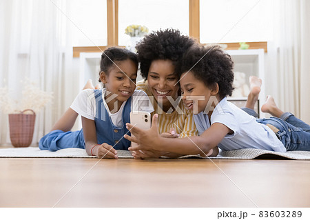 Happy beautiful young african american mother using cellphone with kids. 83603289