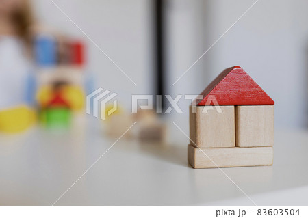 Child girl playing with colorful wooden toy building blocks. Little kid building tower or house at home or day care. Construction block for baby or toddler. Mess in kindergarten play room. 83603504