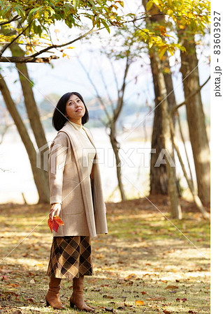 秋の公園を散策する笑顔の中年女性 全身 縦位置 秋の公園を散策する笑顔の中年女性 全身 縦位置 83603927
