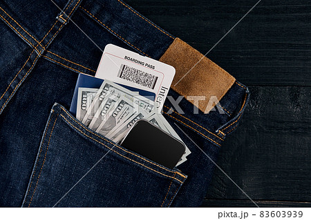 Dollars, smart, passport and plane ticket in your pocket jeans on black wooden background Dollars, smart, passport and plane ticket in your pocket jeans on black wooden background 83603939