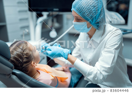 Female dentist treats teeth of little girl patient at dental office. Dentistry concept Female dentist treats teeth of little girl patient at dental office. Dentistry concept 83604446