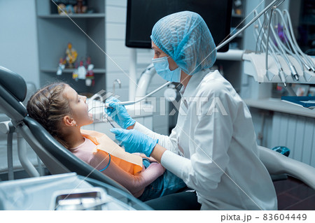 Female dentist treats teeth of little girl patient at dental clinic. Dentistry concept Female dentist treats teeth of little girl patient at dental clinic. Dentistry concept 83604449