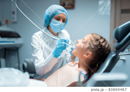 Side view of female dentist who treats teeth of little child patient in dental office. Dentistry Side view of female dentist who treats teeth of little child patient in dental office. Dentistry 83604467