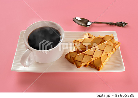 Cup of hot steaming coffee and puff pastries on a white rectangular plate over pink background. 83605539