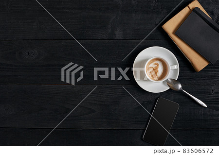 Smartphone with notebook and cup of coffee on wooden background. Cell phone with writing set with espresso 83606572