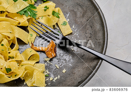 Plate of traditional pasta pappardelle with chanterelle mushrooms eaten not finished 83606976