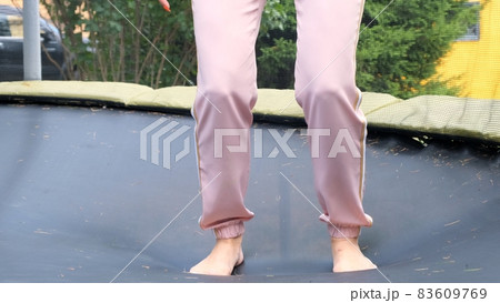 young woman is jumping on a babut, a close-up. Legs float in the air after jumping on a trampoline young woman is jumping on a babut, a close-up. Legs float in the air after jumping on a trampoline 83609769