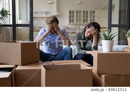 Exhausted couple sit near cardboard boxes at relocation day Exhausted couple sit near cardboard boxes at relocation day 83612512
