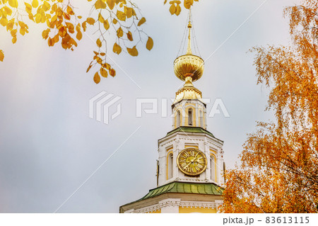 Ancient christian church and autumn yellow trees. Beautiful domes, high bell tower against the sky 83613115