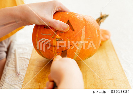 hands carves a lantern out of a pumpkin for halloween.  83613384