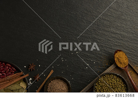 spices concept various types of spices set into small bowls and a wooden spoon and some put on the black ground 83613668